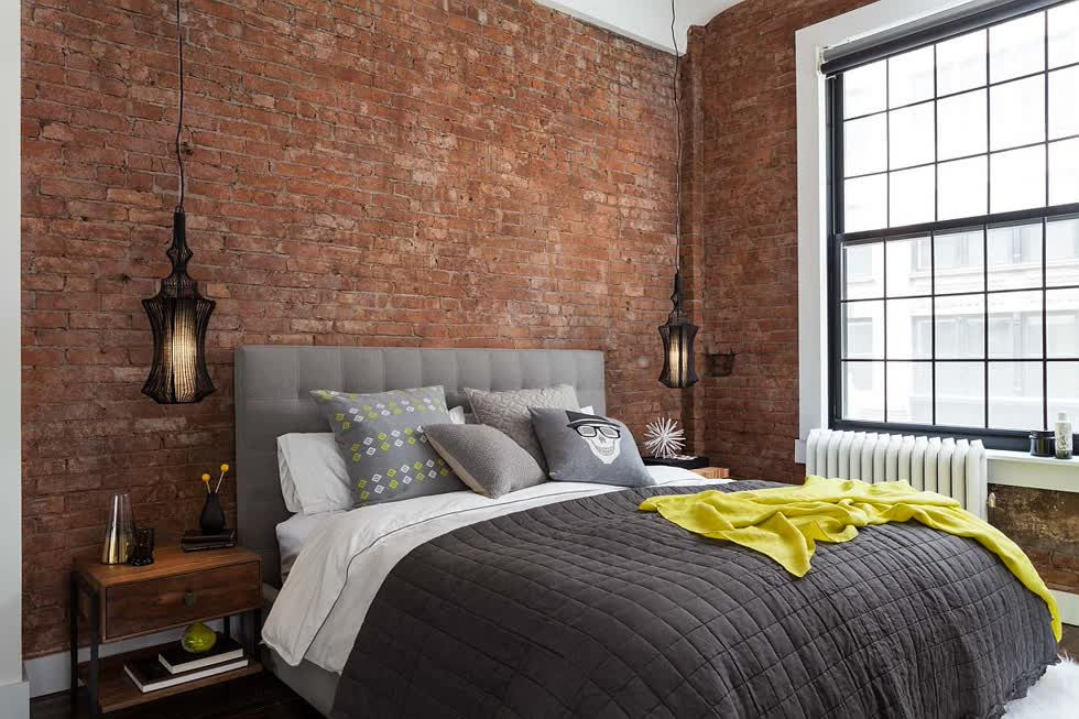 Phòng ngủ hiện đại công nghiệp với những bức tường gạch lộ ra và một cửa sổ lớn bên trong ngôi nhà ở New York.