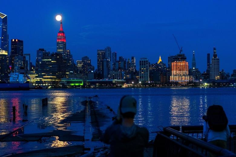 Siêu trăng trên Tòa nhà Empire State, quận Manhattan, thành phố New York, Mỹ trong bối cảnh tòa nhà đang thắp sáng để cổ vũ những người mắc COVID-19.