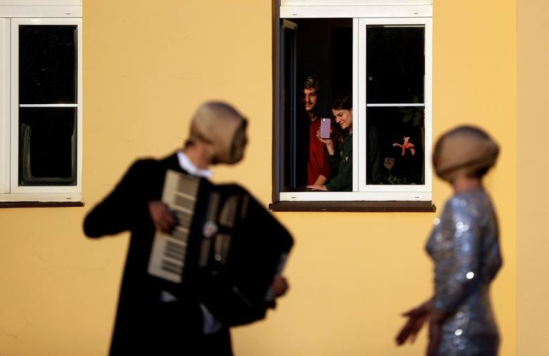  Cư dân của một tòa nhà chung cư xem các nhạc sĩ đường phố biểu diễn từ ban công của họ ở Prague, Cộng hòa Séc (ảnh trái) và cư dân của Prospect xem Pete Martelle biểu diễn một buổi biểu diễn ngẫu hứng cho khu chung cư của mình ở Putney, London.