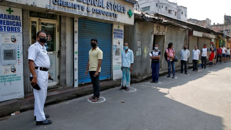   Vòng tròn phấn đặt khoảng cách giữa những người xếp hàng để lấy thuốc ở Kolkata, Ấn Độ. Ảnh: Reuters  