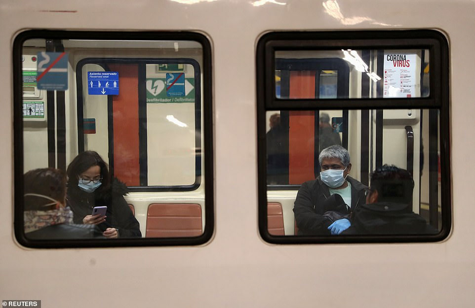  Một người phụ nữ nhận khẩu trang từ cảnh sát thành phố tại một ga tàu điện ngầm ở Madrid (ảnh phải), cũng như ngồi ở một khoảng cách trên tàu điện ngầm Madrid.