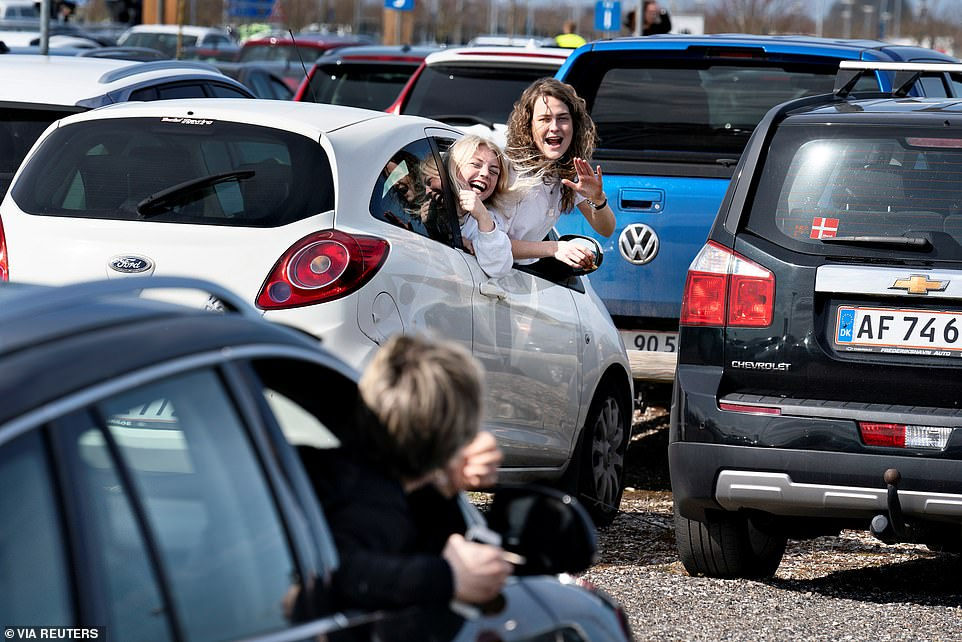   Người dân trao đổi với nhau từ xa trong bãi xe tại sân bay Aalborg ở Đan Mạch.  
