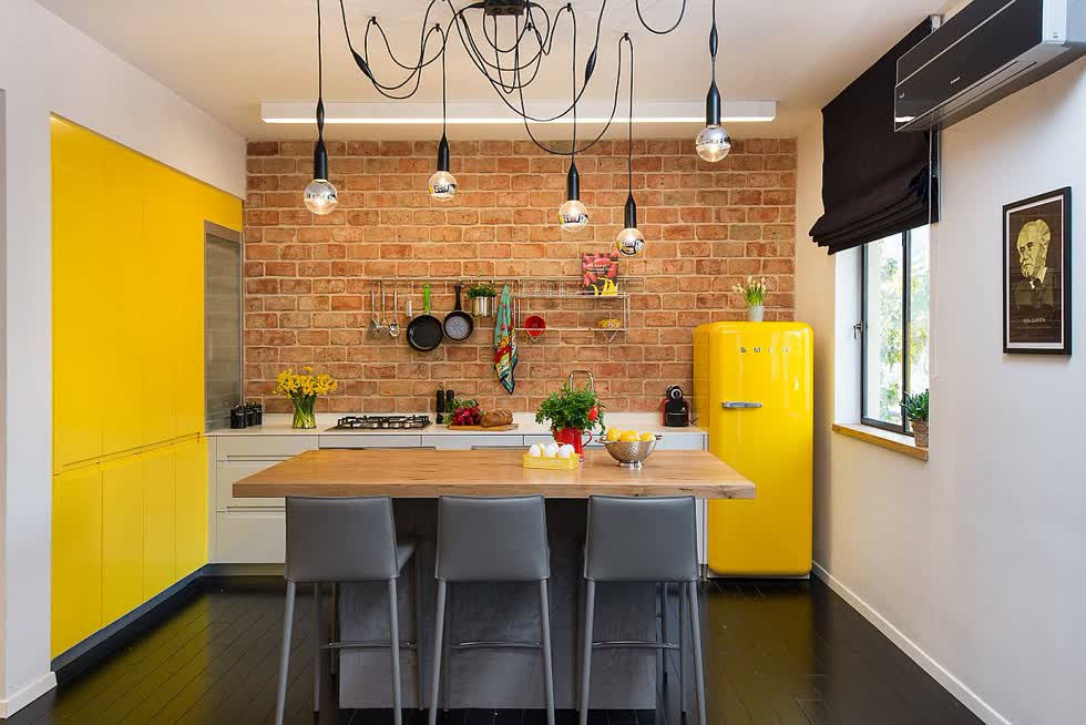   Nhà bếp chiết trung tuyệt đẹp với bức tường làm bằng gạch và màu vàng đáng yêu xung quanh.  