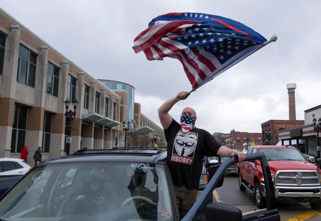 Một người đàn ông Mỹ đeo khăn che mặt khi tham gia cuộc biểu tình phản đối gia hạn lệnh ở trong nhà tại Michigan. Ảnh: Reuters