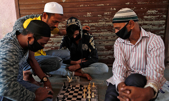   Người dân Ấn Độ đeo khẩu trang ngồi chơi cờ ở Dharavi, một trong những khu ổ chuột lớn nhất châu Á tại Mumbai, hôm 10/4. Ảnh: Reuters.  