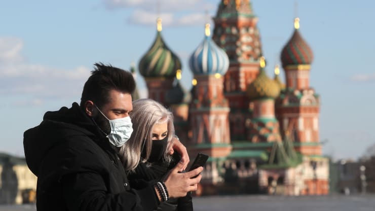 Một cặp vợ chồng đeo khẩu trang nhìn vào điện thoại di động của họ ở Quảng trường Đỏ vắng vẻ trong đại dịch COVID-19.