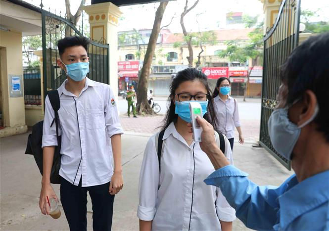 Học sinh trường THPT Việt Đức, quận Hoàn Kiếm được đo kiểm tra thân nhiệt trước khi vào trường theo đúng quy định. Ảnh: TTXVN 