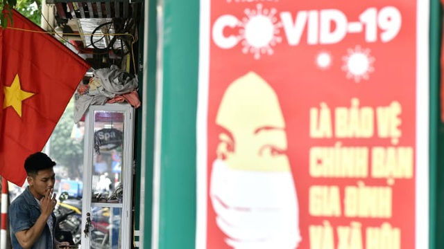 Một áp phích tuyên truyền về việc ngăn chặn sự lây lan của COVID-19 tại Hà Nội. Ảnh: AFP.