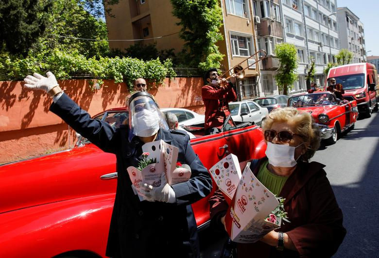   Người dân địa phương nghe một ban nhạc hát dọc đường phố và nhận hoa từ các tình nguyện viên khi một đoàn xe của thành phố Fatih kỷ niệm Ngày của Mẹ ở Istanbul, Thổ Nhĩ Kỳ.  