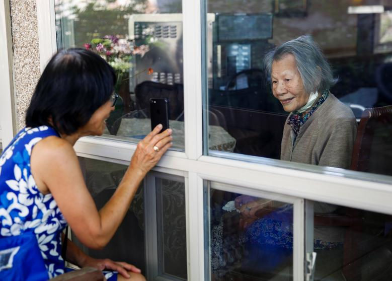   Su Wilson, (bên trái), mỉm cười khi cầm điện thoại với các thành viên khác trong gia đình khi trò chuyện video khi cô đến thăm mẹ Chun Liu, ở Washington.  