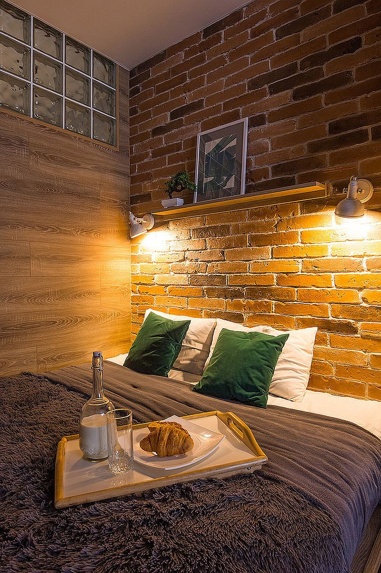 Đèn treo chiếu sáng bức tường gạch đầu giường trong phòng ngủ công nghiệp nhỏ.