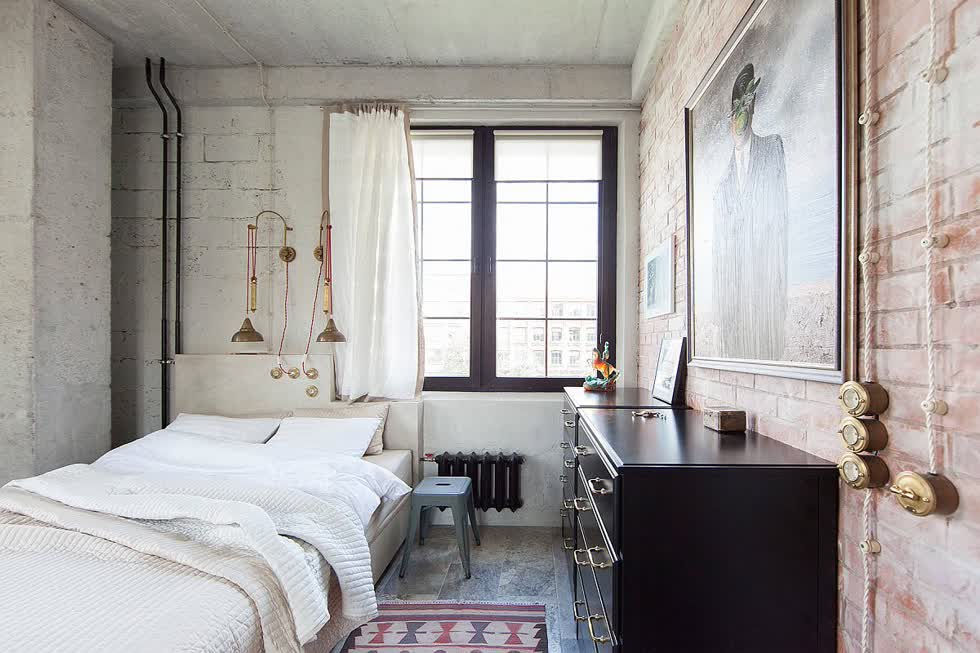 Rèm cửa màu trắng, tường kết cấu và đồ đạc ánh sáng kim loại kết hợp để tạo ra phòng ngủ tuyệt vời này.