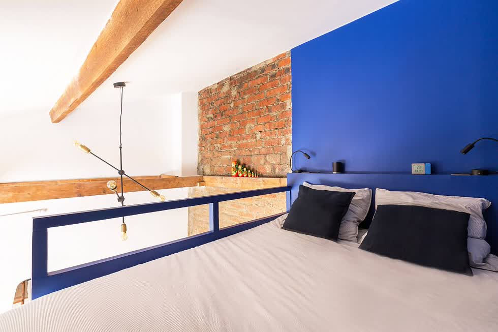 Phòng ngủ công nghiệp nhỏ với bức tường tạo điểm nhấn màu xanh và thiết kế siêu phong cách.