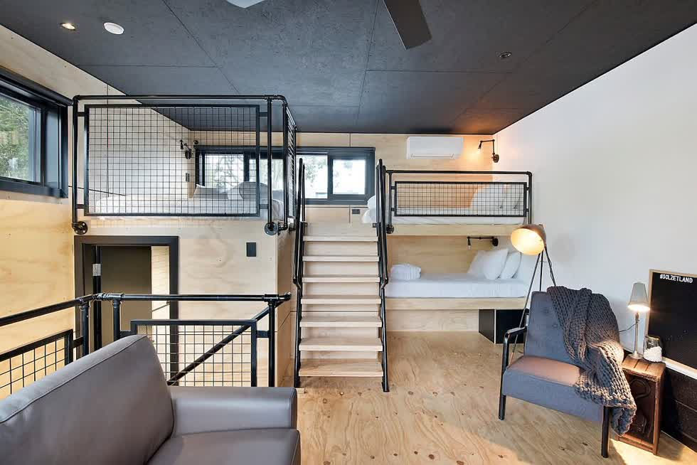Phòng ngủ công nghiệp hiện đại ở tầng áp mái bằng gỗ được sơn đen với lối trang trí thông minh.