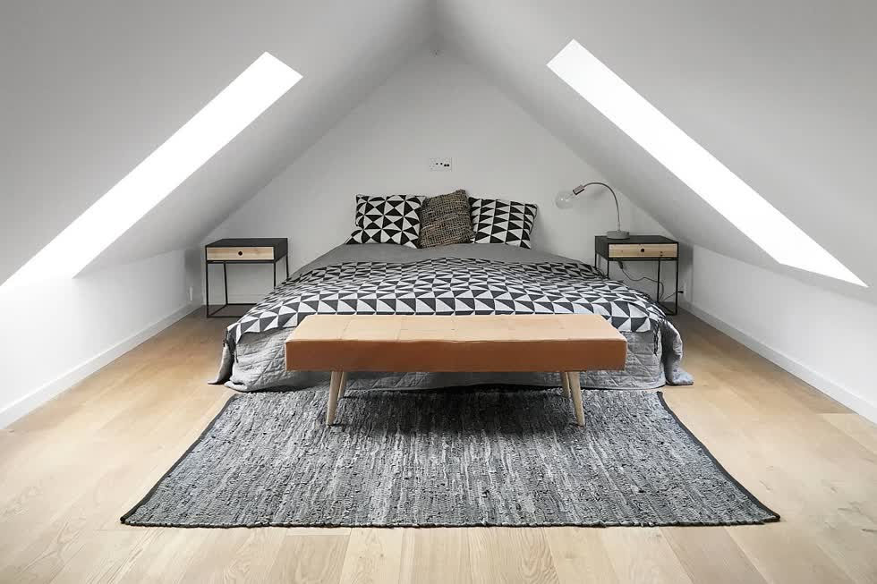 Phòng ngủ gác mái công nghiệp hiện đại với ánh sáng tự nhiên rộng rãi và sàn gỗ đẹp.