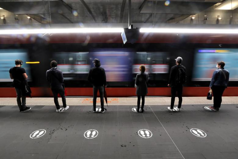   Mọi người đứng trên các biển báo để thực hiện giãn cách xã hội trong khi chờ xe điện ở Nice, Pháp, ngày 11/5. Ảnh: REUTERS  