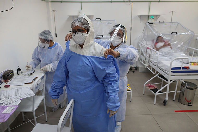   Một nhân viên y tế giúp một phụ nữ mặc đồ bảo hộ tại Đơn vị Chăm sóc Chuyên sâu COVID-19 của Bệnh viện Gilberto Novaes ở Manaus, Brazil, vào ngày 20/5. Ảnh: AFP.  