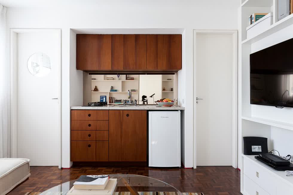 Góc bếp nhỏ được gói gọn trong hốc tường, nổi bật với hệ tủ gỗ màu cánh gián.