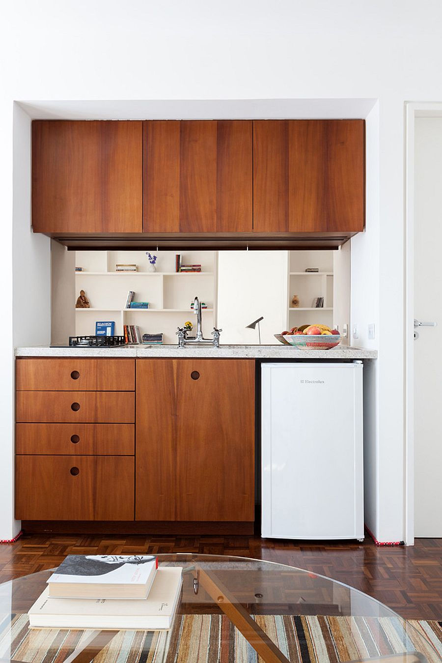 Tủ bếp bằng gỗ tạo điểm nhấn ấm áp cho căn hộ màu trắng chủ đạo.