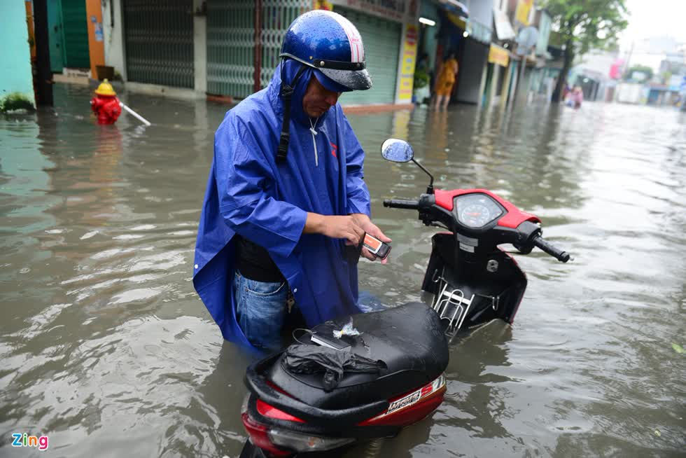 Một người dân vất vả khi đi làm vào buổi sáng trên đường An Dương Vương sau trận mưa cả đêm. Ảnh: Zing