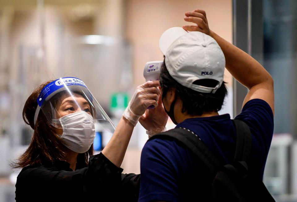 Một nhân viên đeo khẩu trang và che chắn mặt giữa những lo ngại về sự lây lan của COVID-19 tại Nhật Bản.