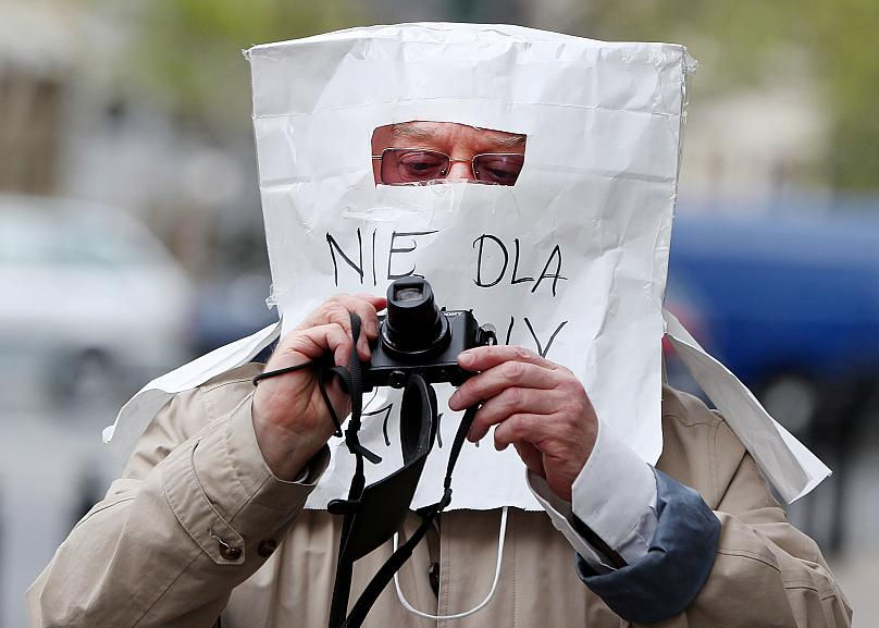 Một nhiếp ảnh gia đeo mặt nạ bảo vệ khác thường chống lại COVID-19 làm từ túi giấy, ở Warsaw, Ba Lan. Ảnh: AP.