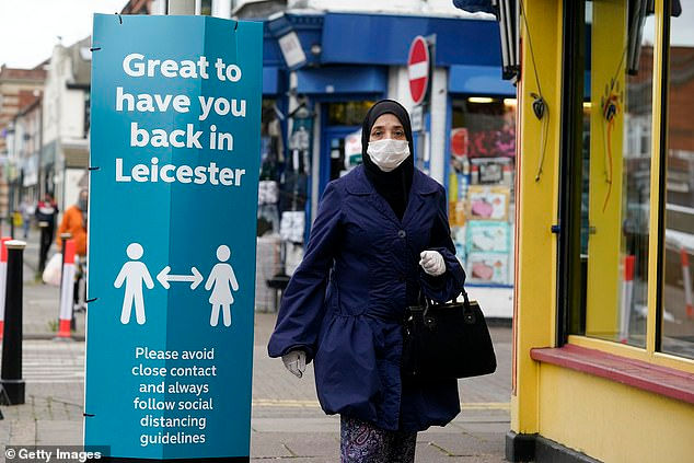 Một người phụ nữ đeo khẩu trang bước qua tấm biển kêu gọi giãn cách xã hội trong khu phố North Evington của Leicester ngày hôm nay (30/6). Ảnh: Dailymail.