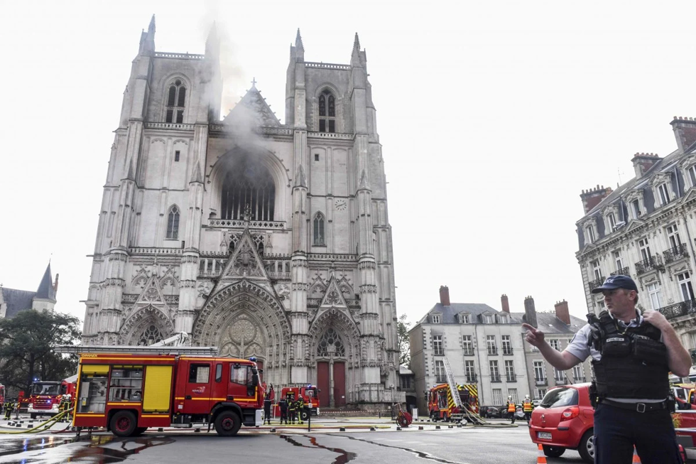 Một sĩ quan cảnh sát Pháp điều khiển giao thông trong khi lính cứu hỏa làm việc để dập tắt đám cháy xảy ra tại nhà thờ, gây thiệt hại nghiêm trọng.Ảnh: AFP.