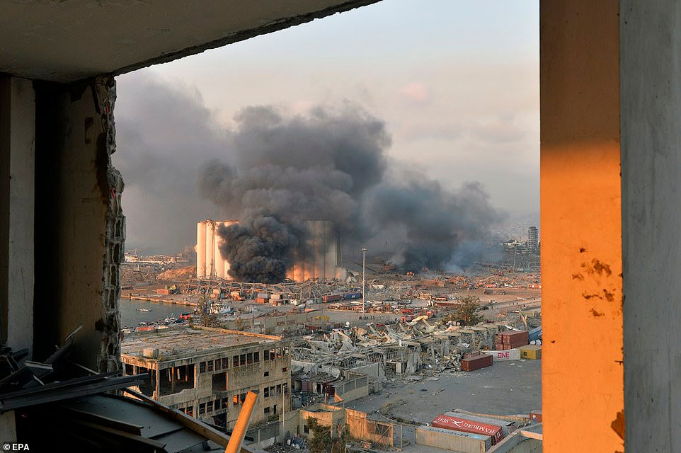 Khói bay từ khu vực bến cảng với thiệt hại và mảnh vụn sau một vụ nổ lớn làm rung chuyển bến cảng Beirut.