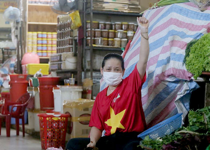 Tiểu thương chợ Đà Nẵng mặc áo cờ đỏ sao vàng cổ vũ thành phố chống dịch. Ảnh: SGGP
