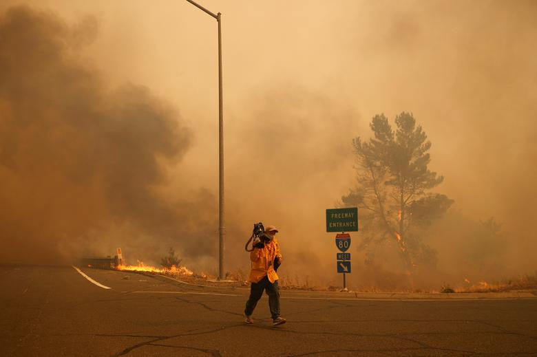 Một người quay phim di chuyển khỏi ngọn lửa dọc theo Xa lộ Liên tiểu bang 80. Ảnh: Reuters.