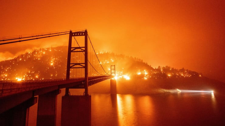   Một chiếc thuyền chạy ngang qua Cầu Bidwell Bar bị bao vây bởi ngọn lửa ở Hồ Oroville trong trận Bear fire ở Oroville, California vào ngày 9/9. Ảnh: CNBC.  