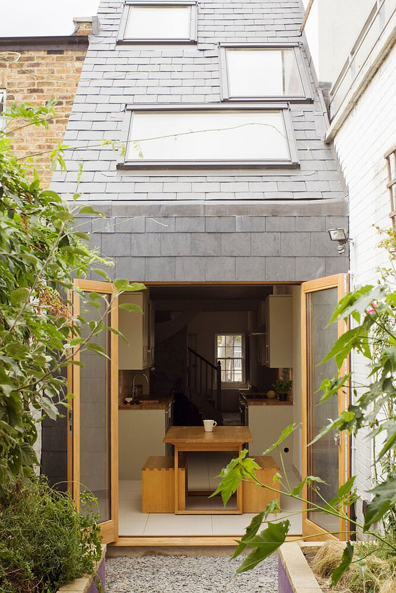 Ngôi nhà mỏng hiện đại ở London với ngoại thất màu xám và gỗ cùng trần dốc có giếng trời so le.