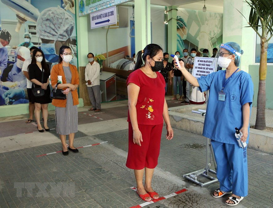 Người dân đến khám bệnh được đo nhiệt độ, khai báo y tế trước khi vào khu vực khám tại Bệnh viện Đà Nẵng. Ảnh: TTXVN