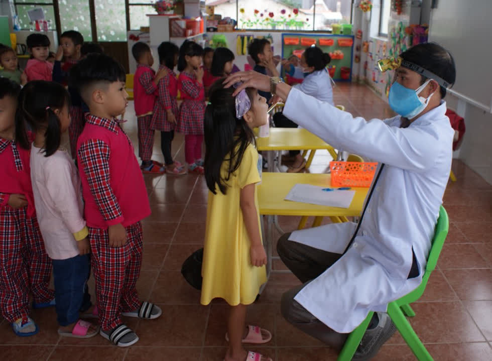 Bác sĩ khám sàng lọc trẻ mầm non trường Anh Đào để phòng bệnh tay chân miệng. Ảnh: Khánh Hương