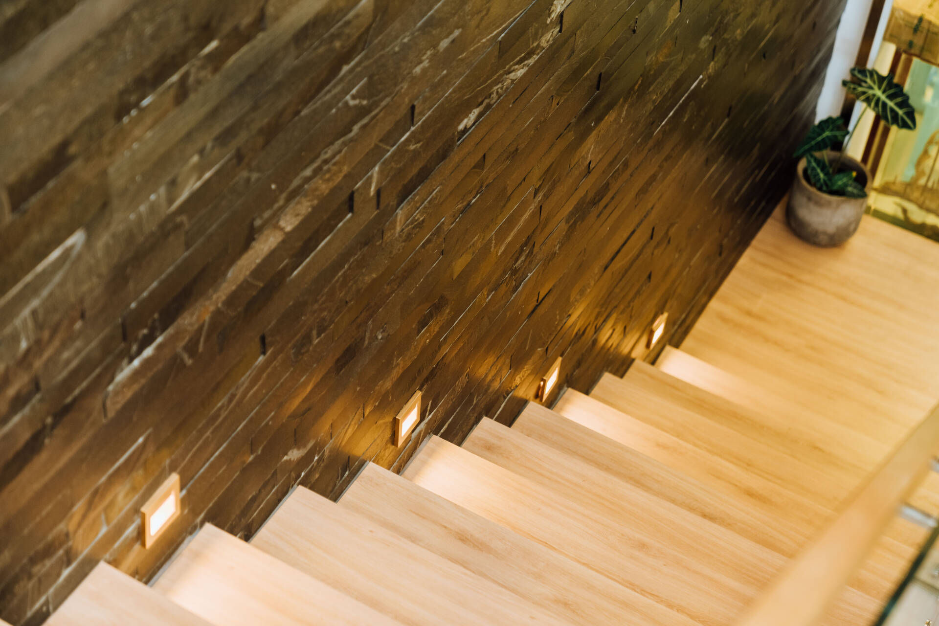 Cầu thang bay dẫn lên nhà sử dụng vật liệu gỗ, kết hợp với lan can bằng kính và tay vịn gỗ. 