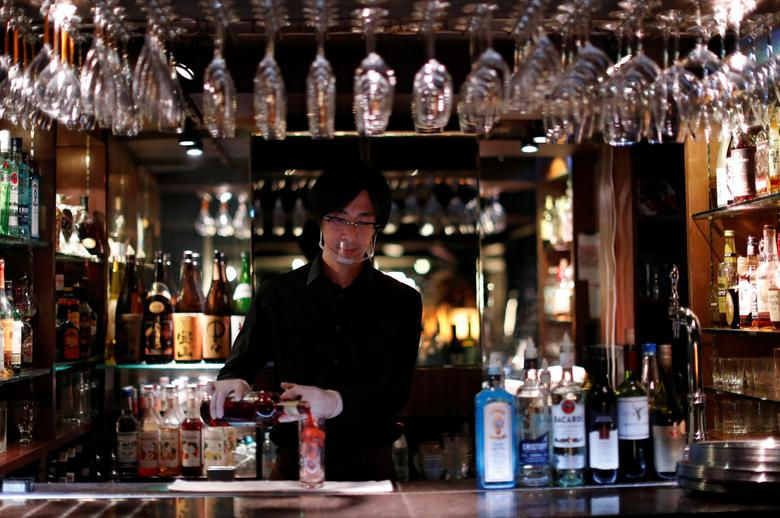 Một nhân viên pha chế đeo kính che mặt pha một ly cocktail tại hộp đêm ở Tokyo, Nhật Bản ngày 6/8. Ảnh: Reuters.