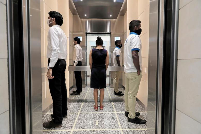 Mọi người tập cách xa xã hội bên trong thang máy trước khi đến nơi làm việc của họ tại Trung tâm Thương mại Thế giới, sau khi chính phủ thông báo rằng các công ty tư nhân và nhà nước sẽ mở cửa trở lại văn phòng của họ sau gần hai tháng bị khóa ở Colombo, Sri Lanka vào ngày 11/5. Ảnh: Reuters.