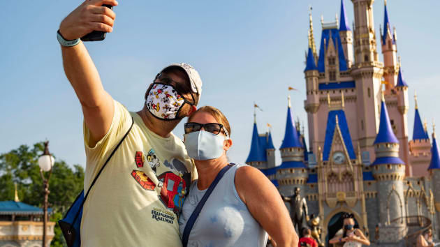   Trong bức ảnh do Walt Disney World Resort cung cấp, du khách dừng chân để chụp ảnh tại Công viên Magic Kingdom ở Walt Disney World Resort vào ngày 11/7/2020 ở Hồ Buena Vista, Florida. Ngày 11/7 là ngày đầu tiên mở cửa trở lại theo từng giai đoạn.  