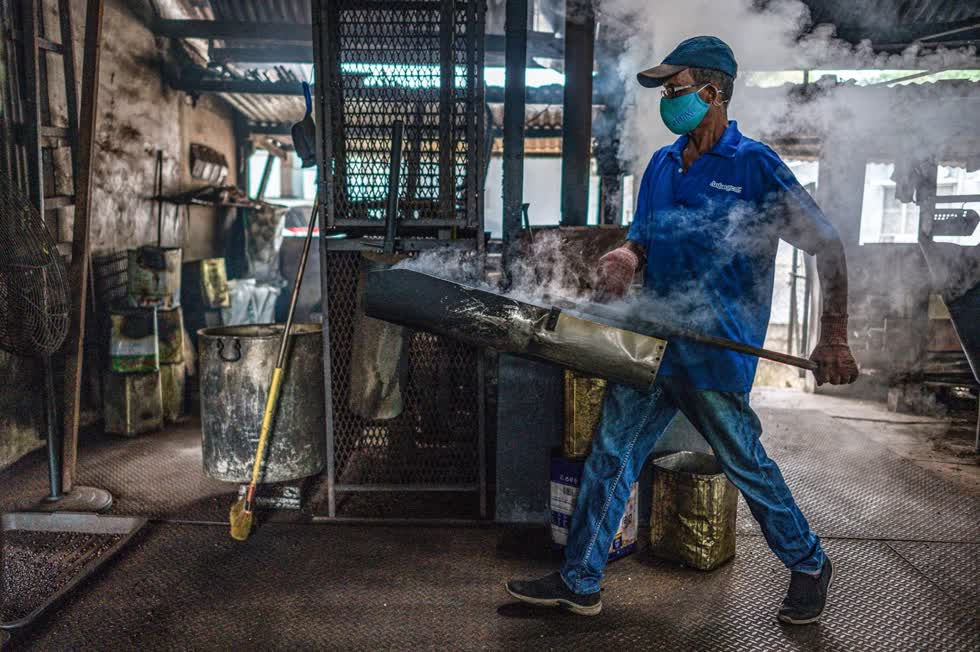 Một công nhân mang hạt cà phê được rang bằng củi tại xưởng Antong. Ảnh: AFP.