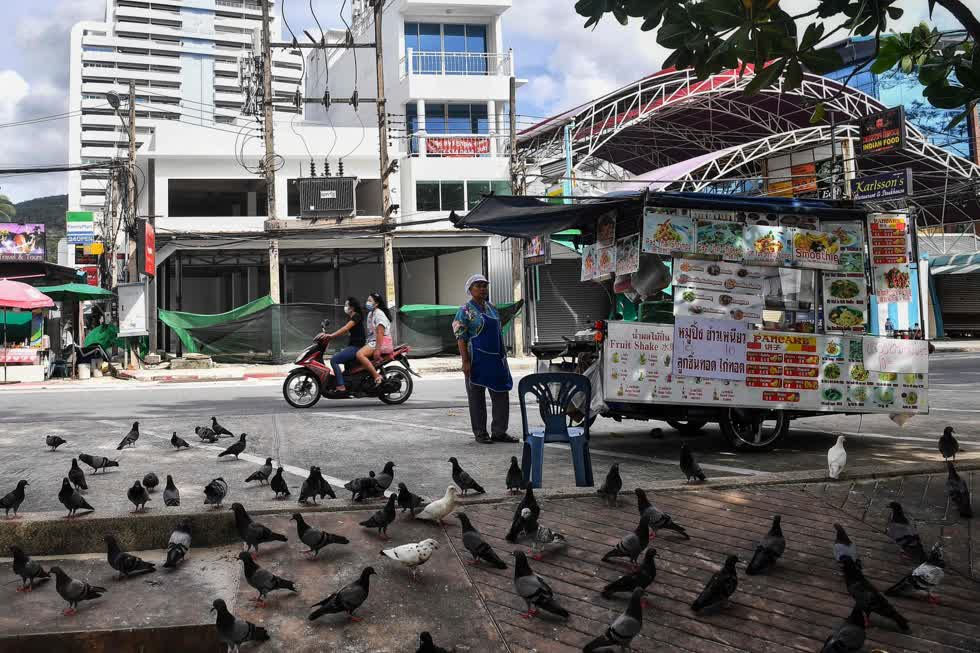 Một người bán thức ăn chờ khách trước những cửa hàng trống trải dọc bãi biển Patong ở Phuket vào ngày 1/10. Ảnh: AFP.