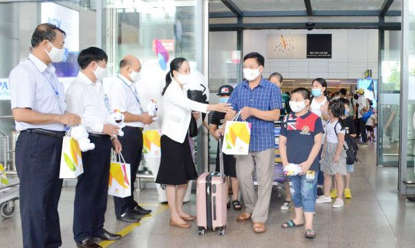 Những vị khách đầu tiên của đoàn 55 du khách đặt chân đến Sân bay quốc tế  Đà Nẵng  và nhận quà của đại diện ngành Du lịch thành phố. Ảnh: Báo Đà Nẵng.