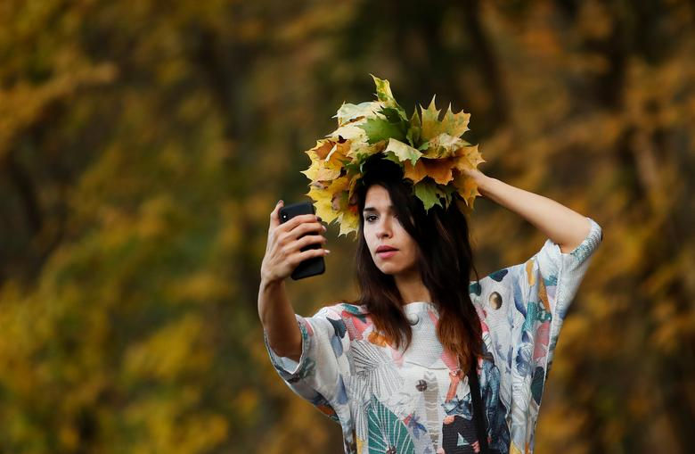 Một phụ nữ chụp ảnh với lá vàng trong công viên ở Moscow, Nga ngày 14/10.