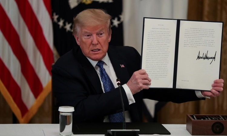 Tổng thống Mỹ Donald Trump giơ một sắc lệnh hành pháp ông vừa ký tại Phòng Đông, Nhà Trắng, ngày 19/5. Ảnh: Reuters.