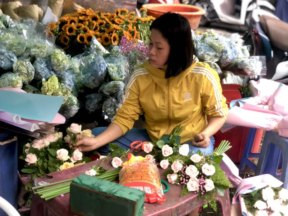 Chủ sạp hoa đang tất bật gói hoa, chuẩn bị cho dịp lễ 20/10. Ảnh: Phương Lê.