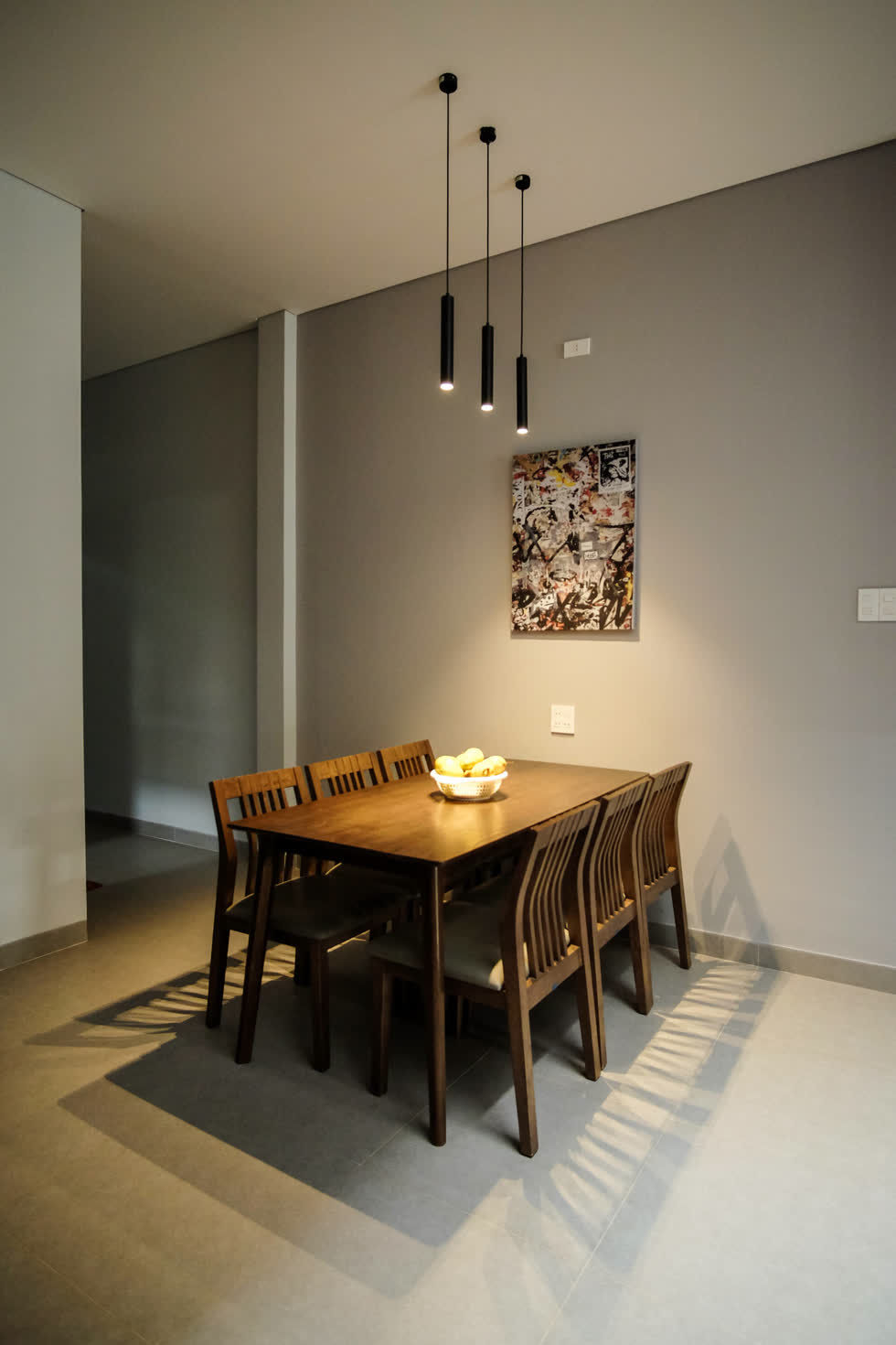 Để cho bớt trống trải, khu vực bàn ăn được trang trí tranh treo tường cùng đèn treo thả hiện đại.