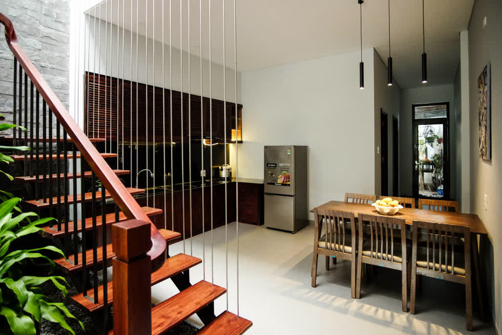 Khu vực bếp gọn gàng, đơn giản với hệ tủ bếp bằng gỗ nâu tối màu, phối cùng mắt bếp và tường được ốp đá đen.