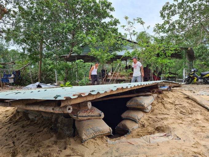 Từ sáng 27/10, gia đình Nguyễn Thị Mau (66 tuổi, ngụ thôn Hà Bình, xã Bình Minh, huyện Thăng Bình, Quảng Nam) huy động con cái, người thân đổ cát vào bao dựng hầm tránh bão. Được biết, căn hầm rộng khoảng 6m2, đào sâu khoảng 2m, được che chắn bởi khoảng 300 bao cát. Để an toàn, gia đình đặt mái tôn phía bên trên, đổ cát che chắn đề phòng gió thổi bay. Căn hầm có thể đủ chỗ chứa cho khoảng tám người. Ảnh: báo Pháp Luật plus