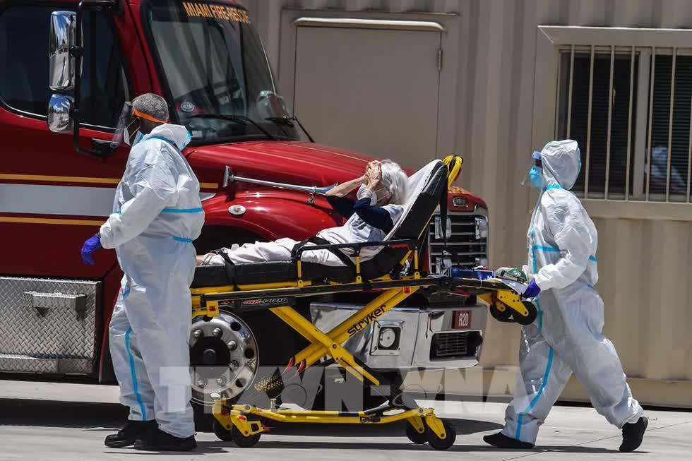 Nhân viên y tế chuyển bệnh nhân COVID-19 tới bệnh viện gần Miami. Ảnh: AFP/ TTXVN