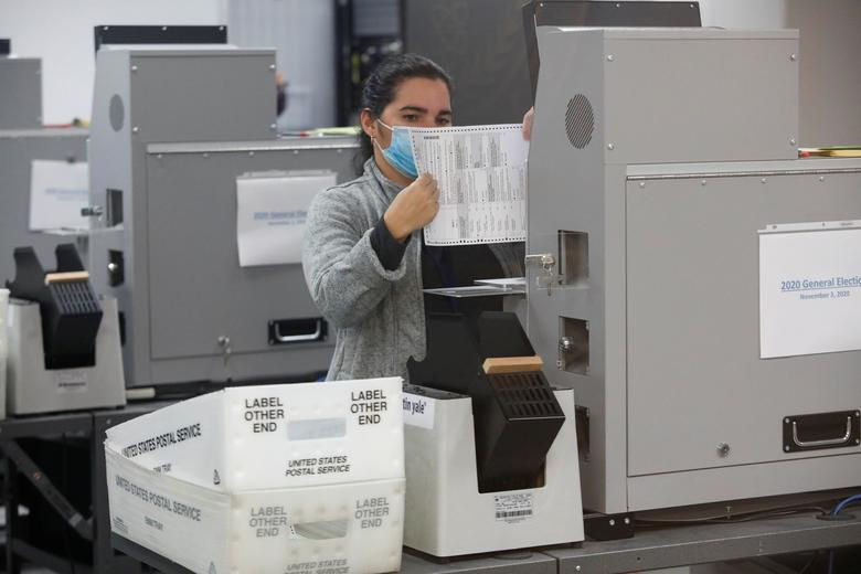 Công nhân của Sở bầu cử hạt Miami-Dade nạp các lá phiếu vào máy đếm. Ảnh: Reuters